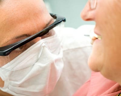 Dentist examining patient's dentures during a reline appointment in Paradise Valley.