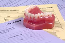 Denture model with teeth displayed on dental patient registration forms and documents.