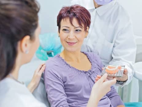 Dentist showing denture model to smiling patient during examination at Paradise Valley dental office.