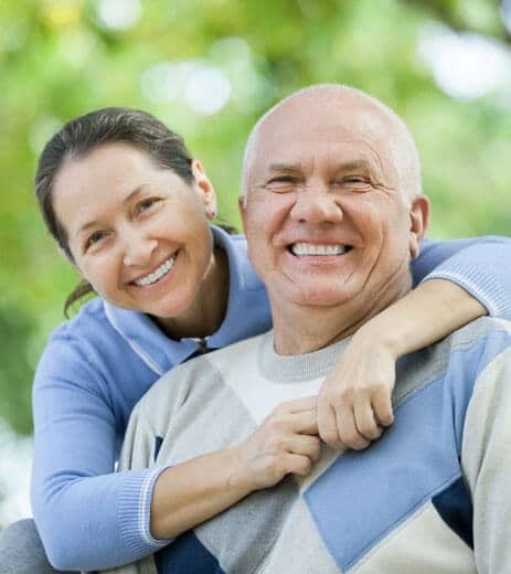 Smiling mature couple embracing outdoors in Paradise Valley dental practice portrait.
