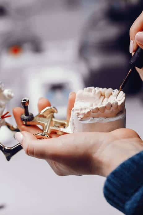 Dentist displaying dental implant materials and tooth model during treatment consultation.