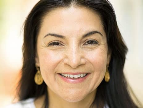Smiling woman with implant-retained dentures showing natural-looking teeth.