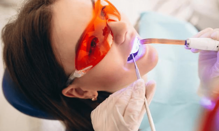 Patient receiving professional teeth whitening treatment with UV light application.