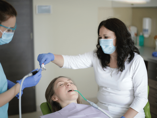 Dentist and assistant preparing dental filling treatment for young patient in Paradise Valley office.