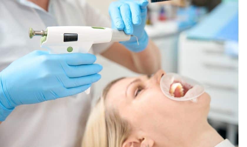 Dentist using digital scanner to examine patient's teeth during filling consultation.