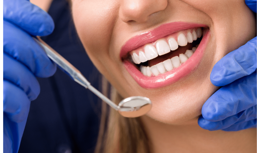 Dentist examining patient's teeth with dental mirror and tools during filling care consultation.