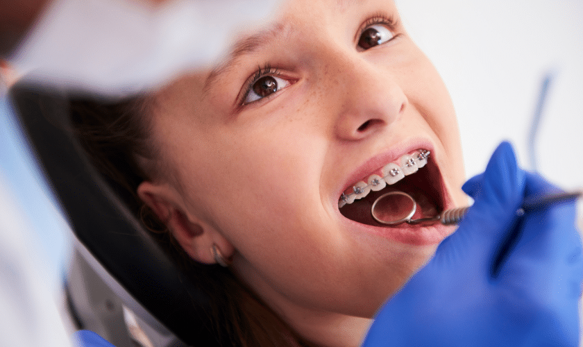 Child with dental braces smiling during orthodontic examination at Paradise Valley dental office.