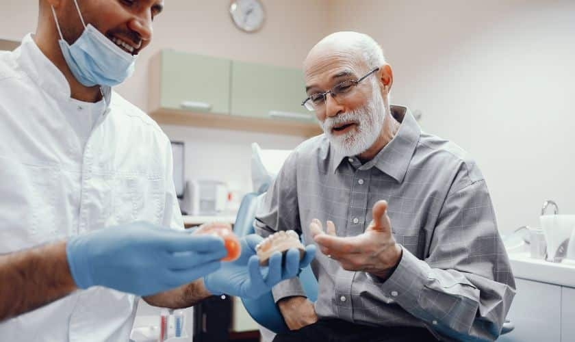 Dentist showing implant supported overdenture model to senior patient in Paradise Valley dental office.