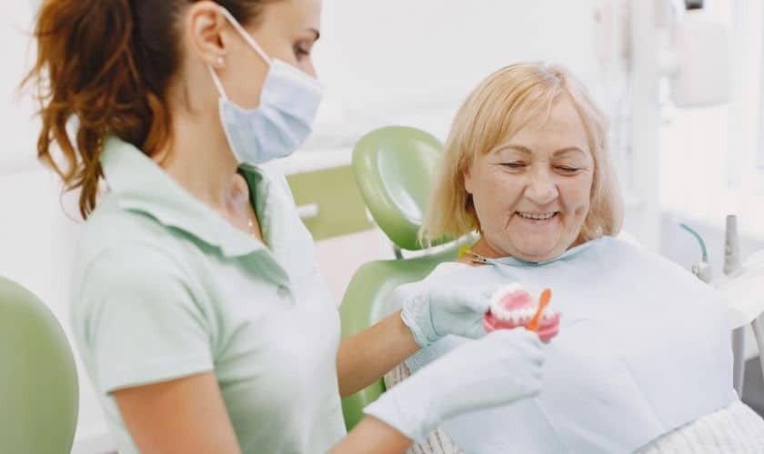 Dental hygienist showing dentures to senior patient during consultation in Paradise Valley dental office.