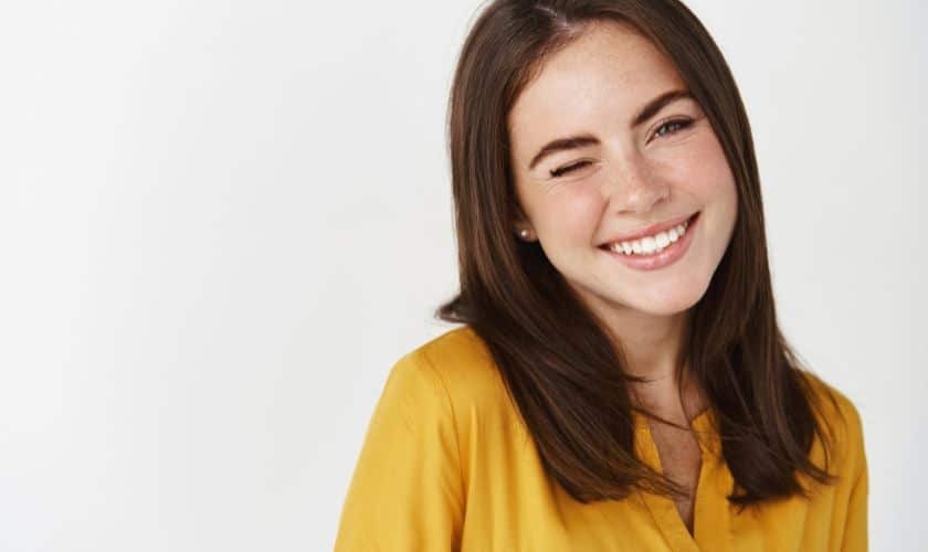 Smiling woman in yellow shirt demonstrating a healthy, confident smile.
