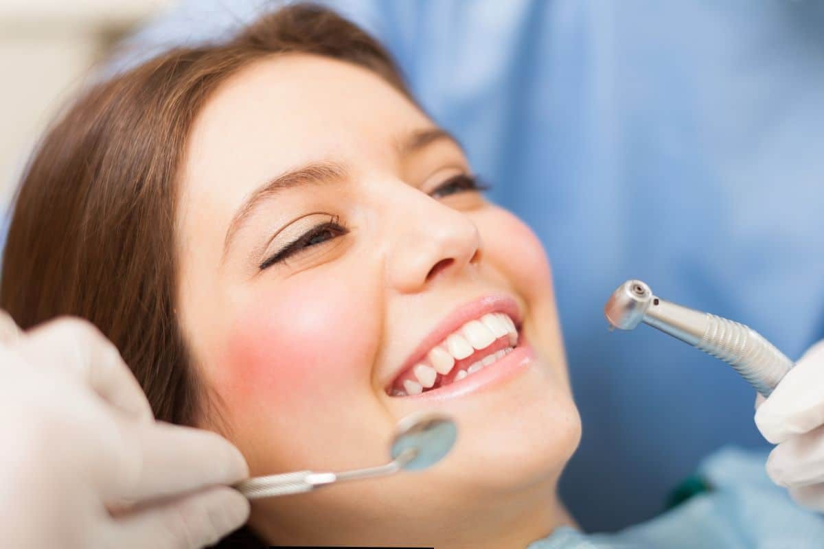 Woman smiling during dental bonding treatment with dentist holding tools in Paradise Valley.