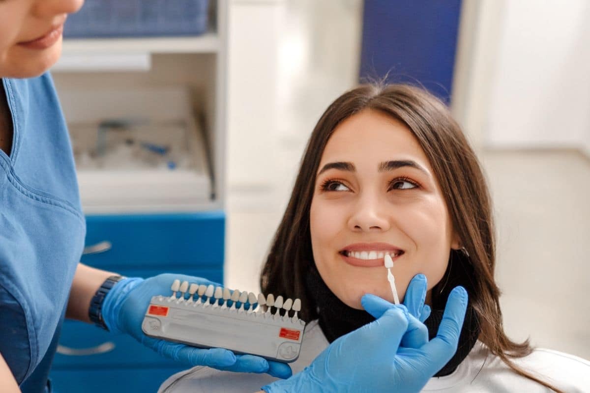 Dentist showing tooth shade guide to smiling patient during veneer consultation in Paradise Valley.