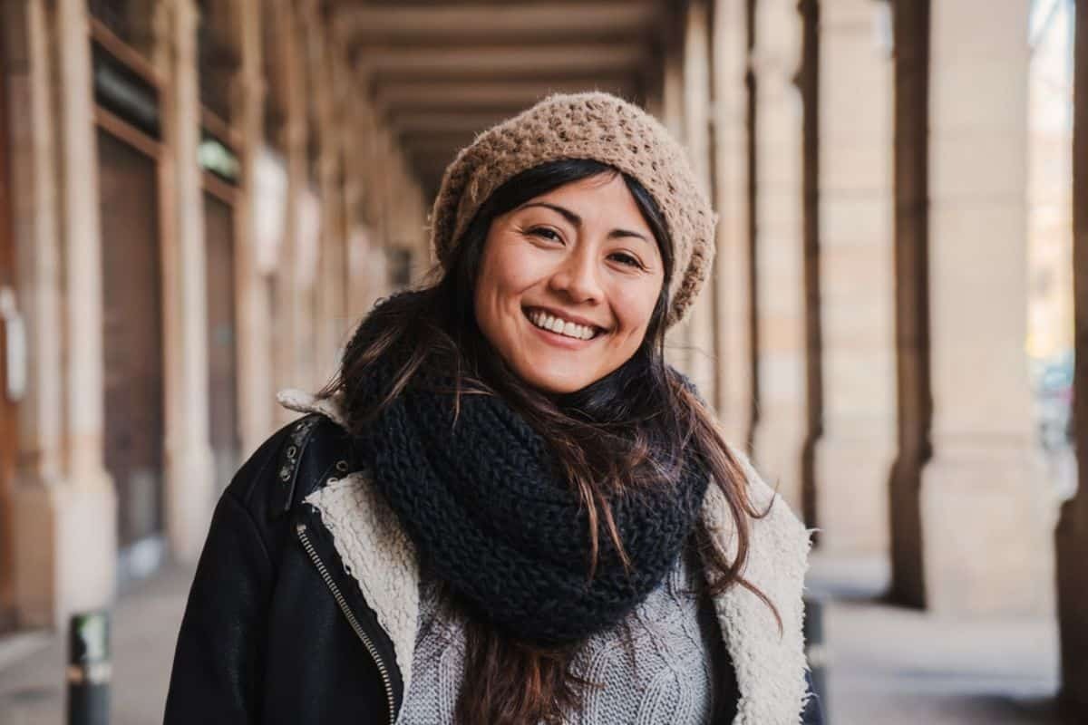Smiling woman in beanie and scarf in Paradise Valley dental practice hallway.