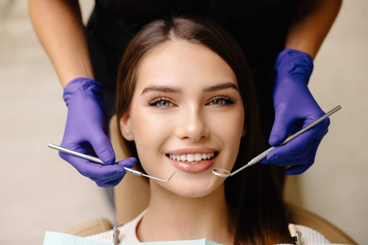 Smiling woman receiving preventive dental examination with dentist holding mirror and explorer tool in Paradise Valley.