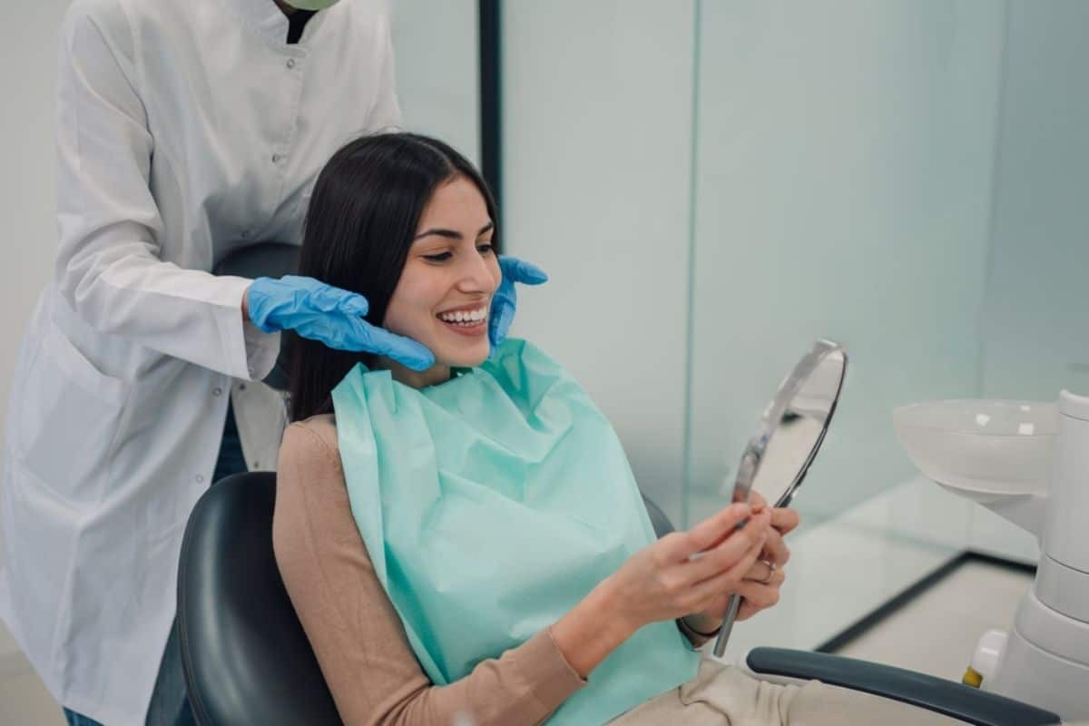 Smiling patient viewing mirror results after cosmetic dental treatment with dentist in Paradise Valley.