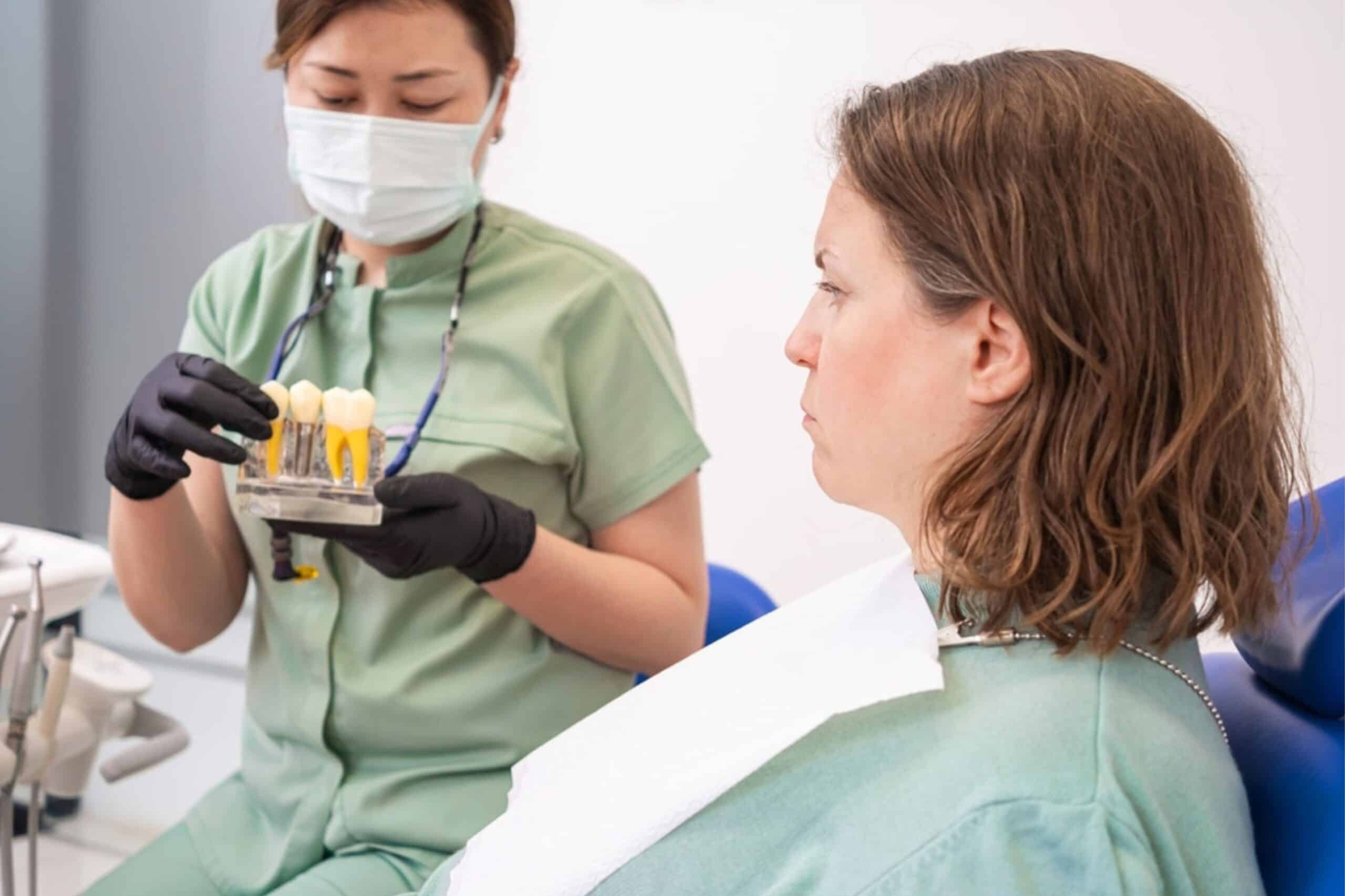 Dentist showing dental implant samples to patient during consultation.