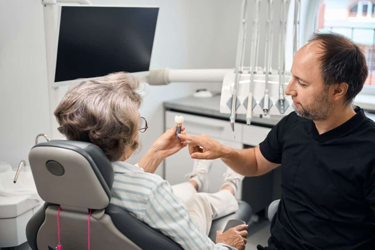 Dentist showing dental implant model to senior patient in Paradise Valley dental office.