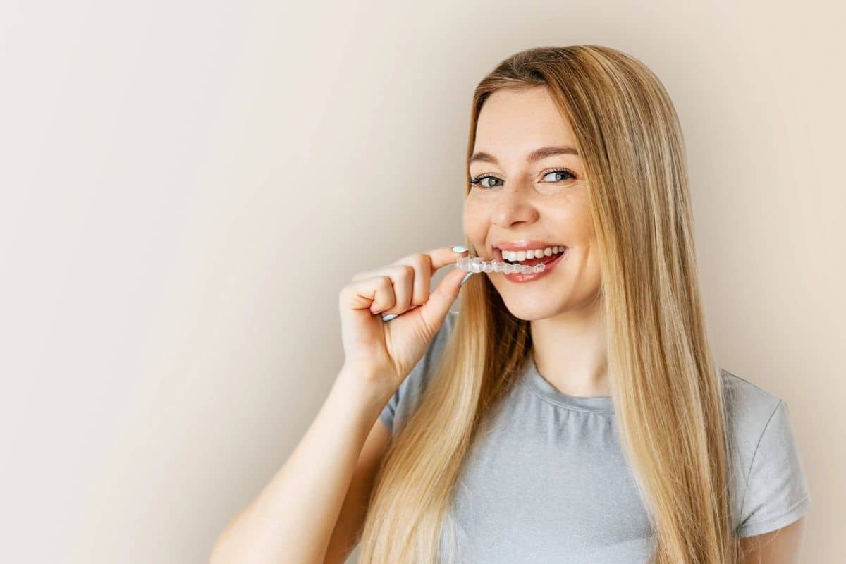 Woman with straight teeth wearing clear aligners as part of Invisalign treatment.