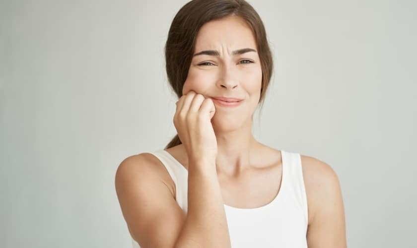Woman with dental pain holding her cheek, illustrating common abscess symptoms.